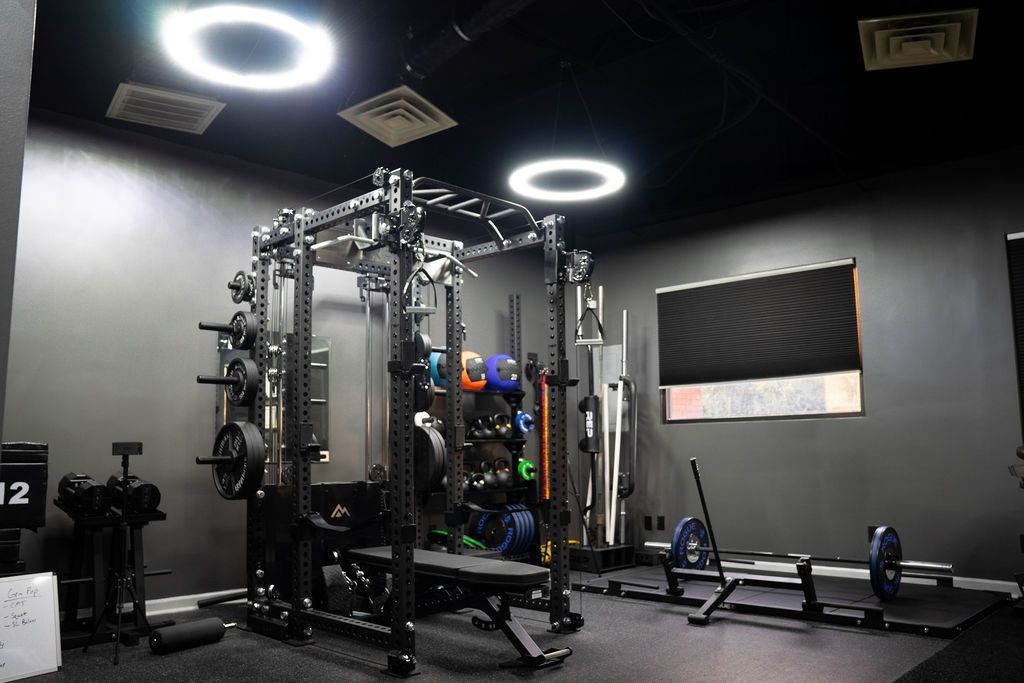 The Licensed Performance training facility in Cary, NC — squat rack, medicine balls, kettlebells, and sled, built for capacity not aesthetic.